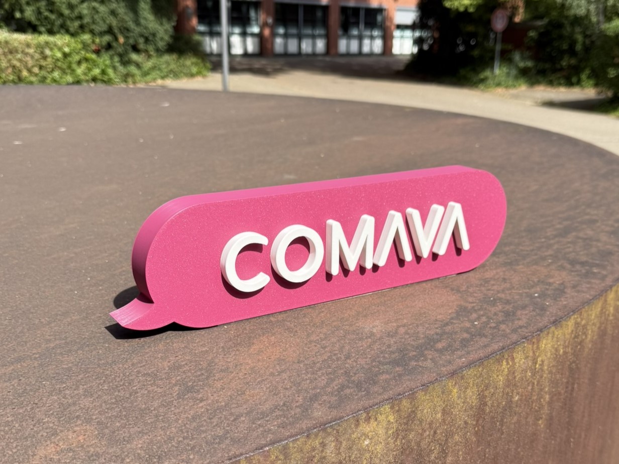 Pinkfarbener 3D-gedruckter Logo-Aufsteller mit erhabenem COMAVA-Schriftzug – Empfangs- und Messemodell von HaTech-3D aus Braunschweig